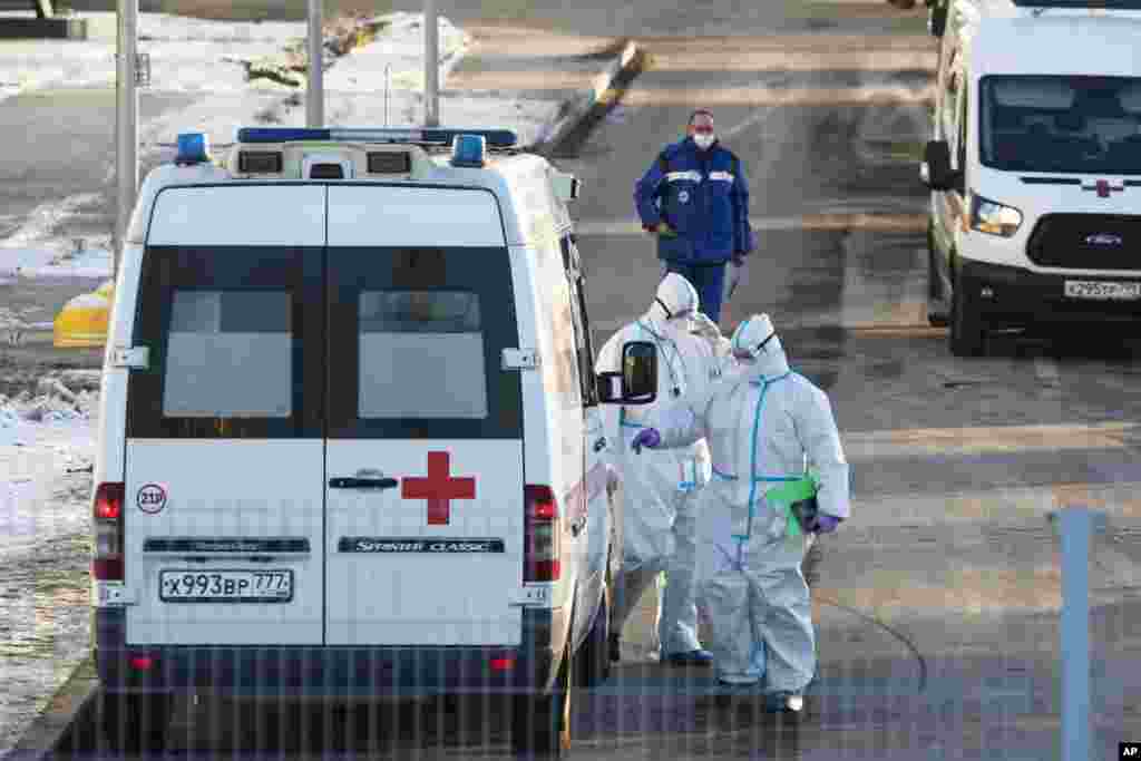 Trabajadores de la salud en Moscú, vuelven a la ambulancia tras haber transferido un paciente que sospechan que tiene coronavirus.