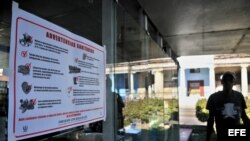 Un hombre pasa junto a un cartel alusivo al control sanitario en la capital cubana. Foto de archivo