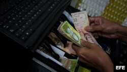 Un hombre guarda dinero en una máquina registradora en Caracas (Venezuela).